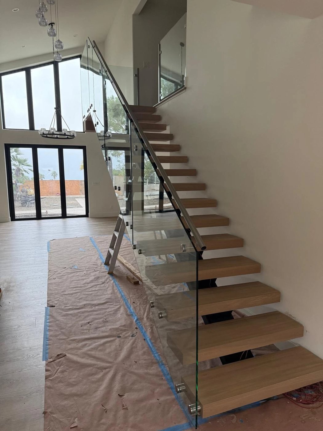 Frameless glass railing on a floating oak staircase during installation