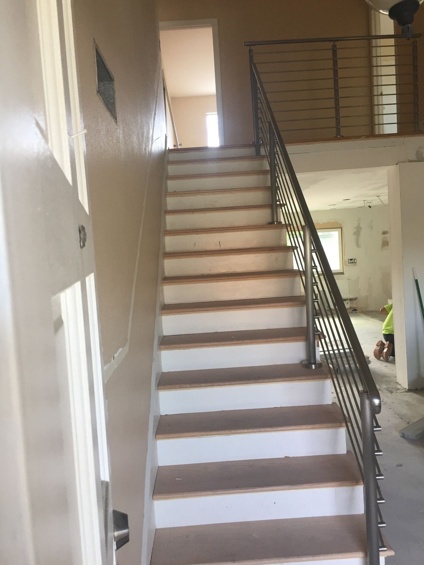 Horizontal stainless steel rod railing along a stair flight and upper landing in a Torrance split-level home